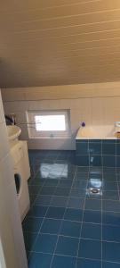 bagno piastrellato blu con servizi igienici e finestra. di Apartma 198 a Kranjska Gora