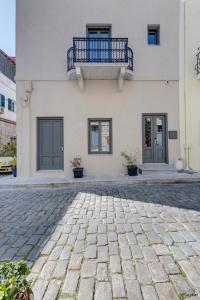 a white building with a balcony and a patio at Times Elegant Rooms in Ermoupoli