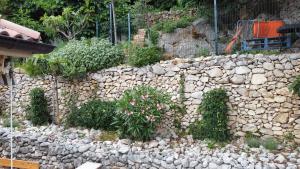 a stone wall with flowers and plants on it at Mel Apartments in Novi Vinodolski