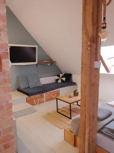 a attic room with a bed and a tv at Apartamenty Pod Sosnami in Sopot