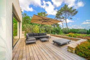 una terraza de madera con sofá y sombrilla en Villa CONTEMPORAINE Piscine Montpellier en Montpellier