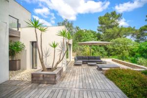 un patio con 2 palmeras y una sombrilla en Villa CONTEMPORAINE Piscine Montpellier en Montpellier
