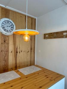 une horloge sur un mur à côté d'une table en bois dans l'établissement Beau studio la campagnarde, à Métabief
