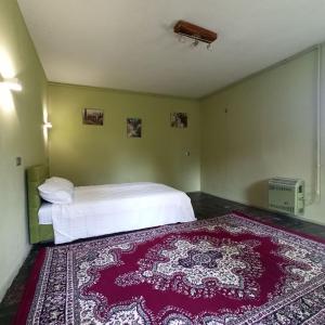 a bedroom with a white bed and a red rug at Маєток SOVA in Khutoro-Gubinikha