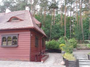 a small red house with a garden and trees at Apartamenty Pod Sosnami in Sopot