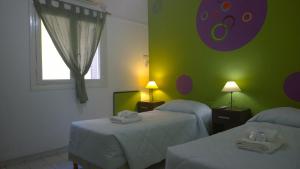 um quarto com duas camas e uma parede verde em Koten Hotel em Buenos Aires