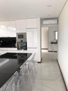 eine Küche mit weißen Schränken und einer Theke mit Stühlen in der Unterkunft Villa - Âncora - 300 mètres de l’océan in Vila Praia de Âncora