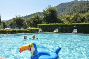 dos niños nadando en una piscina con un pato de juguete en Mobilhome Camping Azzurro, en Ledro