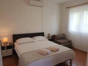 um quarto com uma cama grande e uma cadeira em Apartmani Barada em Seget Vranjica