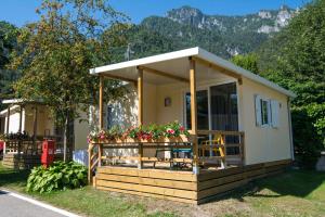 una pequeña casa con flores en la parte delantera en Mobilhome Camping Azzurro, en Ledro