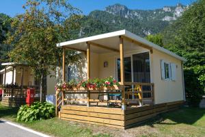 a small house with flowers on the front of it at Mobilhome Camping Azzurro in Ledro