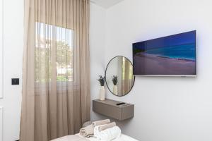 OLIVETUM luxury apartment في سبليت: غرفة بيضاء مع تلفزيون على الحائط