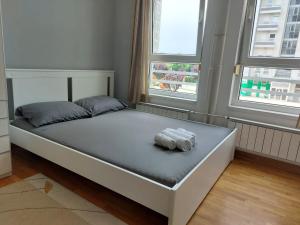 a bed in a room with two windows at Apartman AMORE Belvil in Novi Beograd