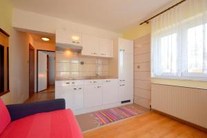 a kitchen with white cabinets and a red couch at Apartments Frane in Vantačići