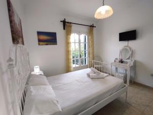 a white bed in a room with a window at Corfu countryside apartment in Potamós
