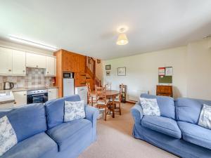 a living room with a blue couch and a kitchen at Stable Cottage - 26032 in Wark