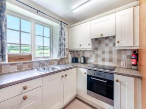 a kitchen with white cabinets and a sink and a window at Stable Cottage - 26032 in Wark
