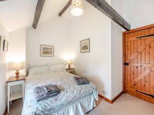 a bedroom with a bed and a wooden door at Stable Cottage - 26032 in Wark