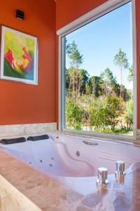 a large white tub in a room with a window at Timber Lodge Camanducaia in Monte Verde