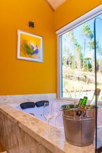 a tub with two wine glasses and a bucket at Timber Lodge Camanducaia in Monte Verde
