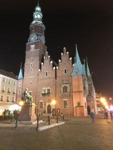 ein großes Gebäude mit einem Glockenturm bei Nacht in der Unterkunft Rynek pod Fredrą in Breslau + 187 Fotos