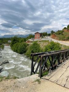 a bridge over a river with a house in the background at Guesthouse Tropojë e Vjeter in Tropojë