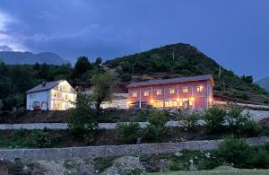 a building with lights on in front of a mountain at Guesthouse Tropojë e Vjeter in Tropojë
