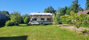 a rv with a roof parked in a yard at Summer bungalo trailer in Jūrmala