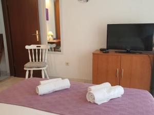um quarto com uma televisão e duas toalhas numa cama em Apartmani Barada em Seget Vranjica