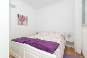um quarto branco com uma cama com um cobertor roxo em Apartment Perla em Dinjiška