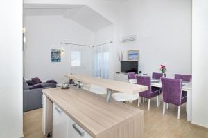 a kitchen and dining room with a table and purple chairs at Apartment Perla in Dinjiška