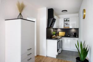 a kitchen with white cabinets and a stove top oven at STAYTONA - Parkpl. - Balkon - WLAN - Netflix - WFH in Taunusstein
