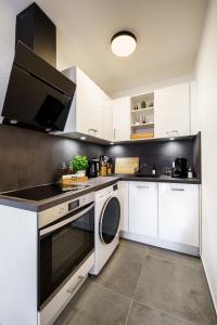 a kitchen with white cabinets and a dishwasher at STAYTONA - Parkpl. - Balkon - WLAN - Netflix - WFH in Taunusstein
