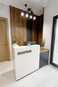 a reception desk in a room with potted plants on it at ĆAKA Luxury Rooms & Restaurant in Ćuprija