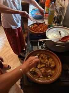 eine Person, die Essen in einer Pfanne auf dem Herd kocht in der Unterkunft Afoulki Ecotourism Guest House in Telouet