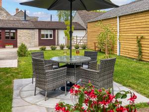 a table and chairs with an umbrella in a yard at Bee Cottage in East Lydford