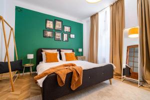 een slaapkamer met een groene muur en een bed met oranje kussens bij The- POINT- 3BR Bright Cloud in Boekarest +22 foto's