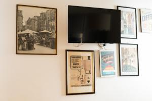 uma televisão de ecrã plano pendurada numa parede com fotografias em Arena Rooms em Verona