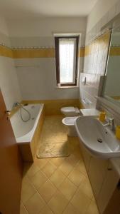 y baño con 2 aseos, bañera y lavamanos. en Oasi Relax a Udine, en Udine
