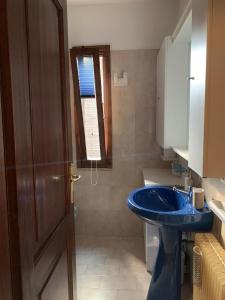uma casa de banho com um lavatório azul e uma janela em La casa lassù em Tarvisio