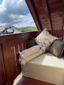- un balcon avec un canapé et des oreillers dans l'établissement Apartman Sunčica, à Zlatibor