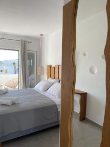a white bedroom with a bed and a window at Pelagos Studios in Platis Gialos