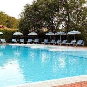 a large blue swimming pool with chairs and umbrellas at 38-Casa Volpin Relax e Sport in Toscana in Castel del Piano