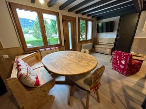 een woonkamer met een houten tafel en stoelen bij Charmant chalet Le Bouton D'or in Métabief