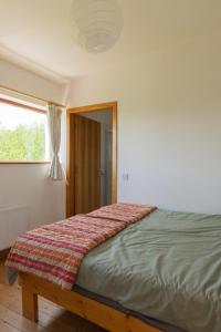 a bed in a white room with a window at The Common Knowledge Centre in Kilfenora