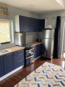 にあるCopper rose guest houseのキッチン(青いキャビネット、ステンレス製の冷蔵庫付)