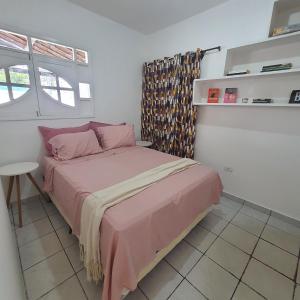Un dormitorio con una cama con sábanas rosas y una mesa. en Casa de Campina, en Campina Grande