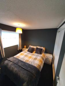 a bedroom with a bed with a plaid blanket and a window at Hemsby Hideaway in Great Yarmouth