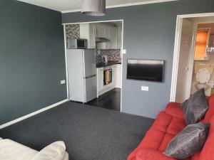 a living room with a red couch and a kitchen at Hemsby Hideaway in Great Yarmouth