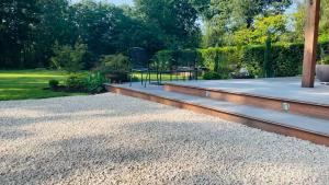 a patio with gravel and a table in a garden at Domaine Bourgogne en Grez "Terre d'Héritage" in Grez-Doiceau
